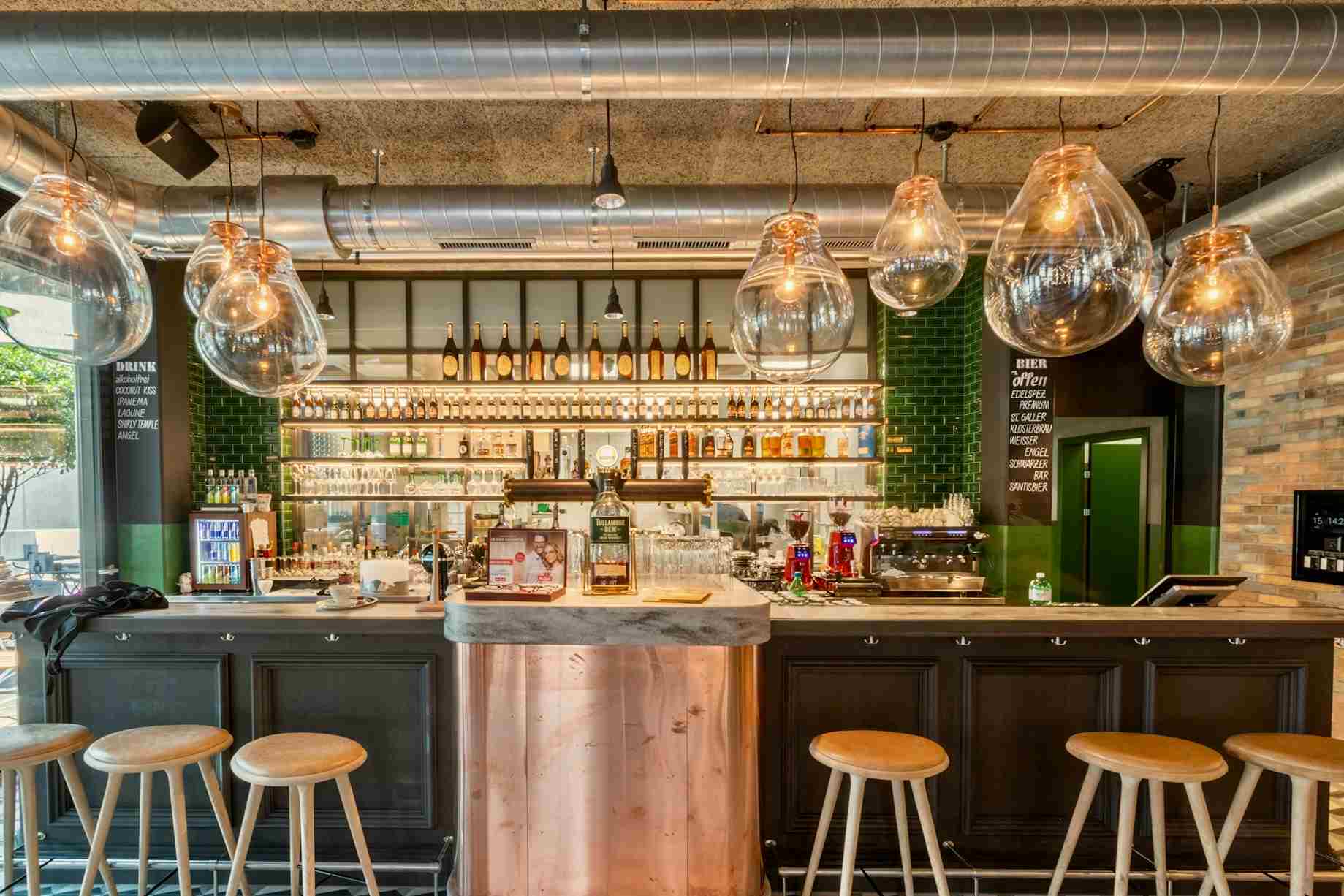 Contemporary commercial bar fitout featuring exposed ceiling ductwork, glass pendant lights, timber stools and a spacious service counter.